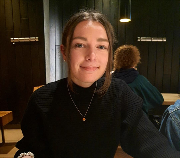 Photograph of Jessica Williams wearing a black top and necklace taken in a restaurant