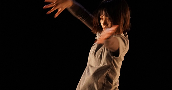 Performance photograph showing Mengling-Li moving around a dark space