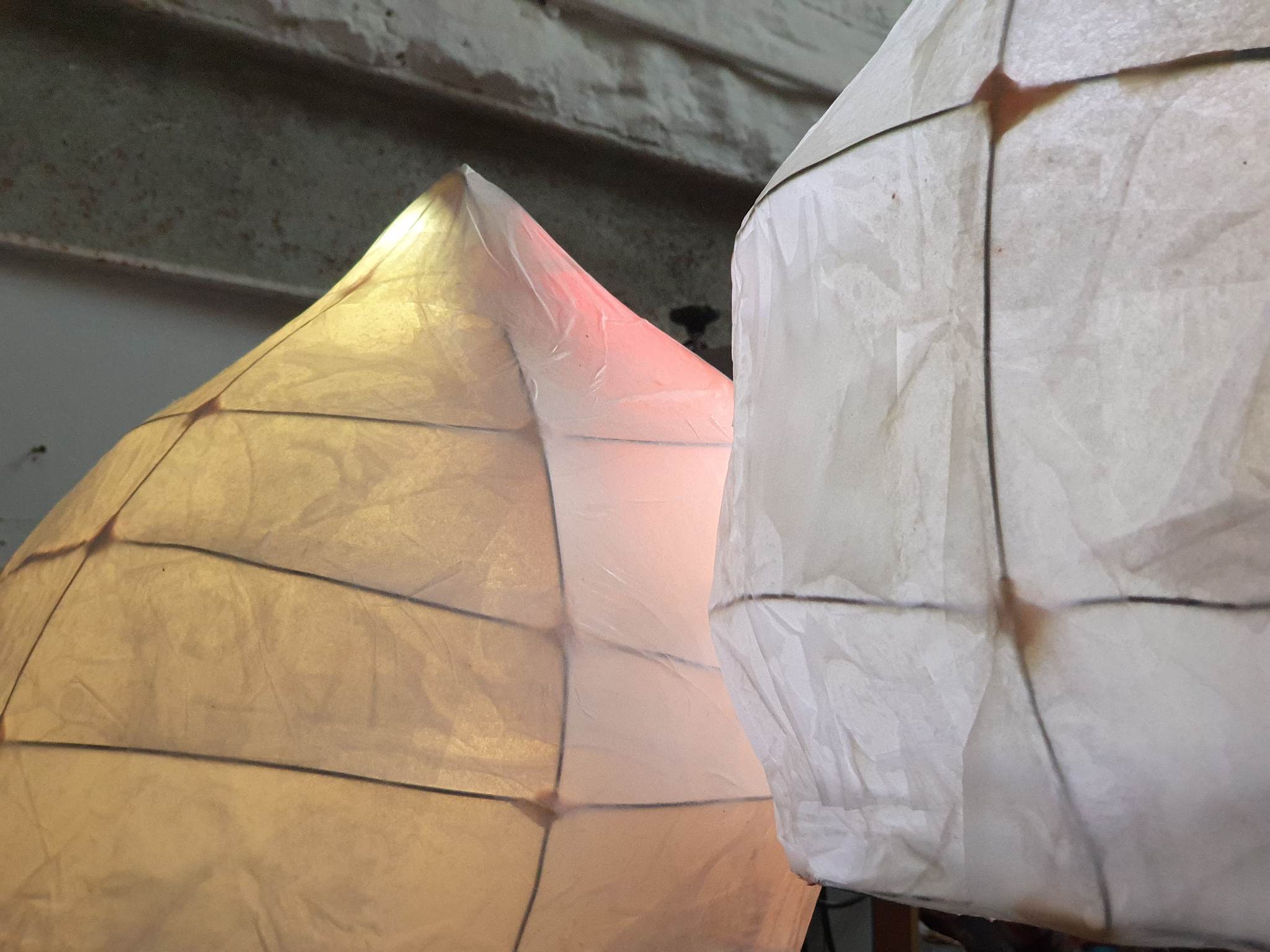 An interactive sculpture, slightly mushroom shaped, made of thin paper-like material, with wired structure and changing lights underneath.